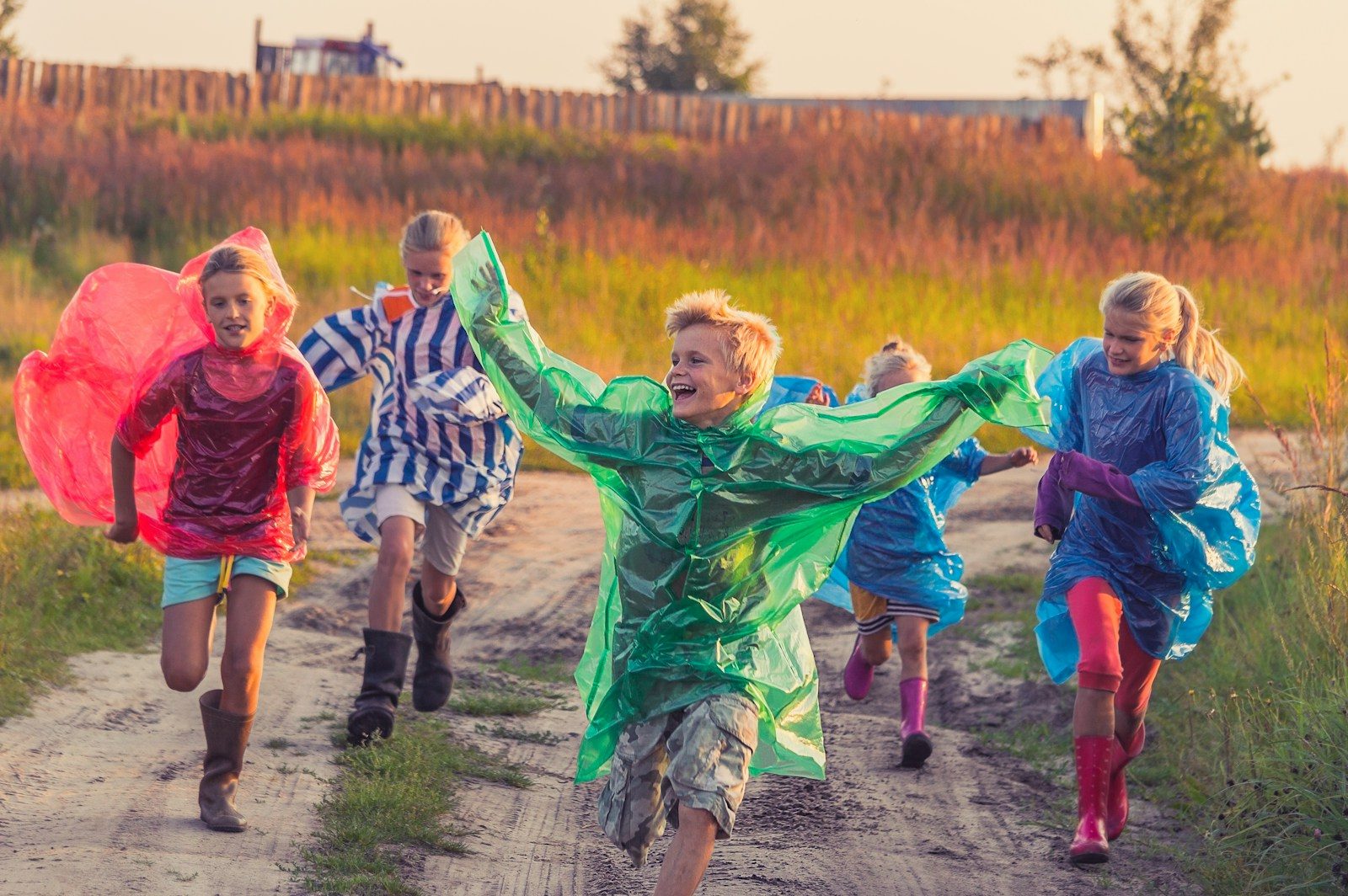 boy in green jacket and red shirt running on road during daytime